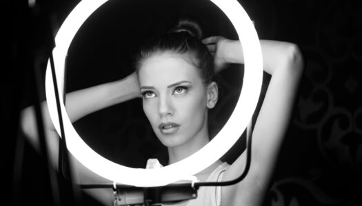 a woman adjusts her hair in front of a ring light